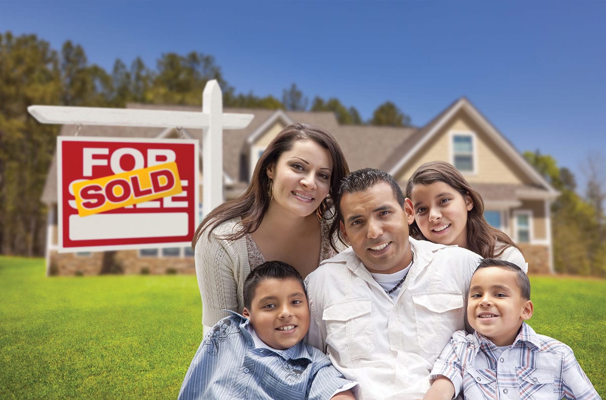 Hispanic family in front of new home and sold sign